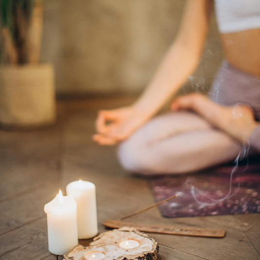 A serene woman meditating in a peaceful setting with a lit candle and incense, creating a calming and spiritual atmosphere.