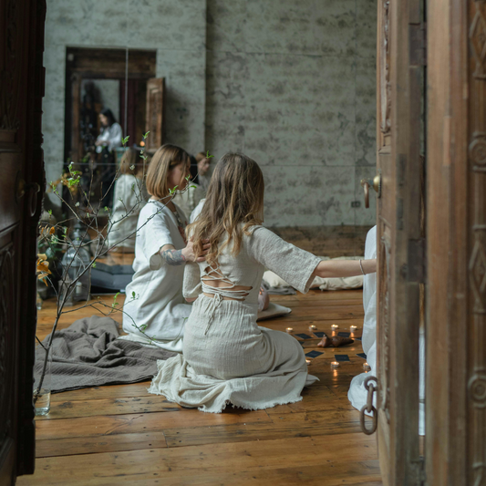 A group of women sitting in a circle around candles, embracing a calm and peaceful atmosphere, fostering connection, mindfulness, and spiritual well-being.
