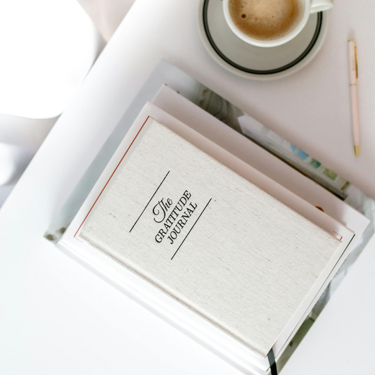 A cozy, aesthetic scene featuring a cup of coffee beside a gratitude journal, creating a peaceful and reflective morning atmosphere.